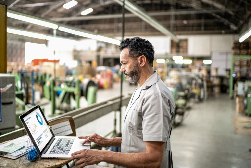 A person working on a laptop in a warehouse setting.