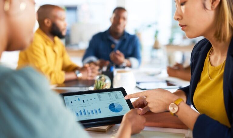 A decorative image of people working together in an office on a tablet.